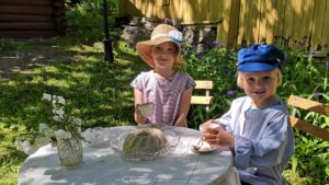 Kaksi lasta vanhahtavissa asuissaan Naantalin museon puutarhassa.